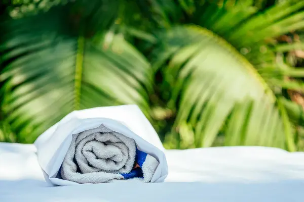 Ręcznik spa na tle stołu do masażu w tropikalnej plaży na świeżym powietrzu — Zdjęcie stockowe