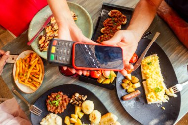 Hintli adam restoranda kredi kartı uygulaması ile akıllı telefon okuyucusuyla ödeme yapıyor.
