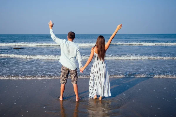 Tatil çifti gün batımında birlikte kumsalda yürüyor. — Stok fotoğraf