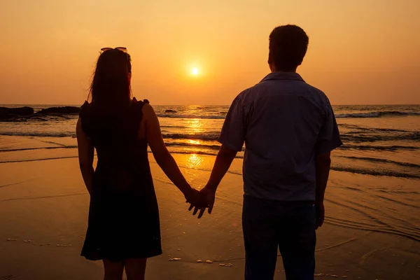 Nyaralás pár séta a strandon együtt szerelmesek naplementekor goa — Stock Fotó