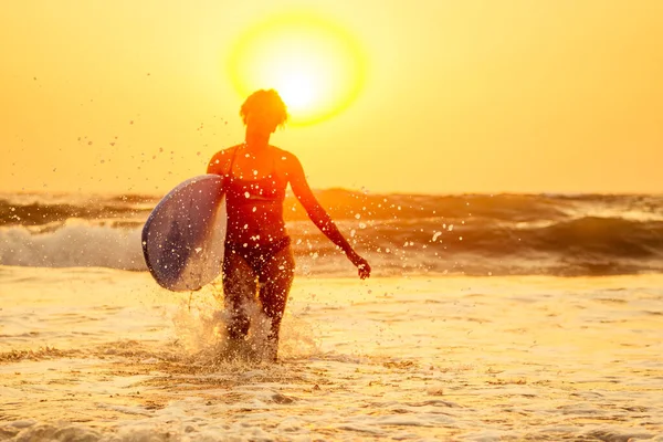 Afro amerikaanse vrouw lopen met surfplank op het strand in Goa — Stockfoto