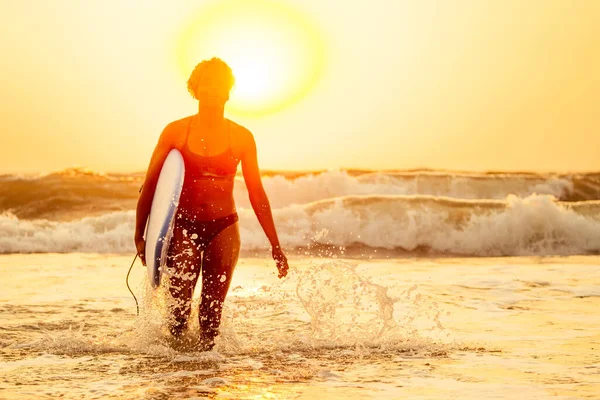 Afro amerikaanse vrouw lopen met surfplank op het strand in Goa — Stockfoto