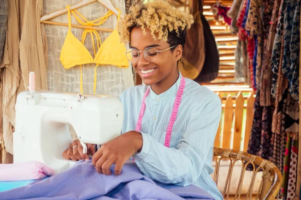 Afrikalı Amerikalı kadın, Bali 'deki tropikal atölyede yaz havuzu partisi için şık sarı bir mayo dikiyor.