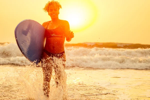 Afro amerikaanse vrouw lopen met surfplank op het strand in Goa — Stockfoto