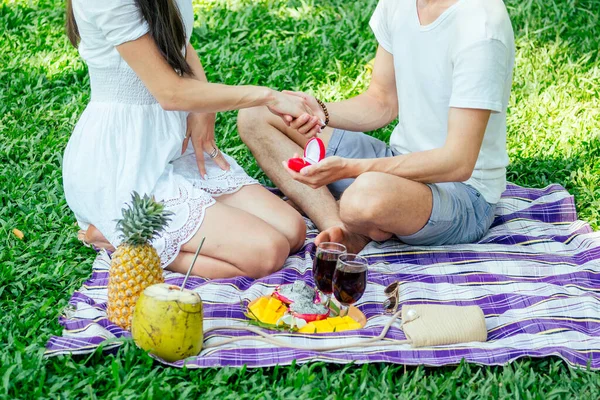 Un homme demande en mariage une femme dans un parc tropical lors d'un pique-nique — Photo