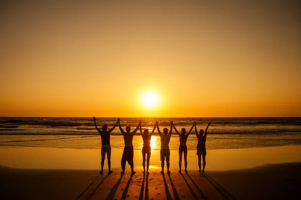 Enam orang kesehatan dalam posisi berdiri hatha dengan tangan terangkat berlari dan napas dada penuh di pantai Goa India saat matahari terbenam — Stok Foto