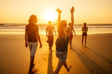 Çok kültürlü, çok uluslu mutlu insanlar güneşe karşı kaygısız ve mutlu bir şekilde koşuyorlar, denizde tatil yapıyorlar.