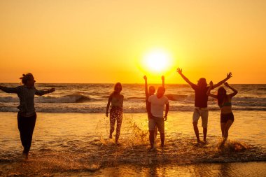 Çok kültürlü, çok uluslu mutlu insanlar güneşe karşı kaygısız ve mutlu bir şekilde koşuyorlar, denizde tatil yapıyorlar.