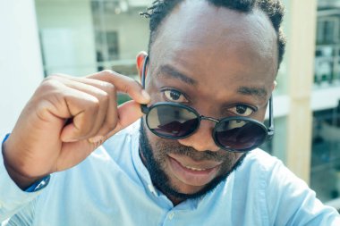 Afro-Amerikan adam elinde büyük bir akıllı telefon ve alışveriş merkezinde poz veriyor.