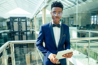 Afro-Amerikan adam elinde büyük bir akıllı telefon ve alışveriş merkezinde poz veriyor.