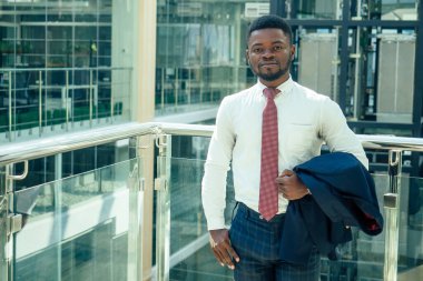 Afro-Amerikan adam elinde büyük bir akıllı telefon ve alışveriş merkezinde poz veriyor.