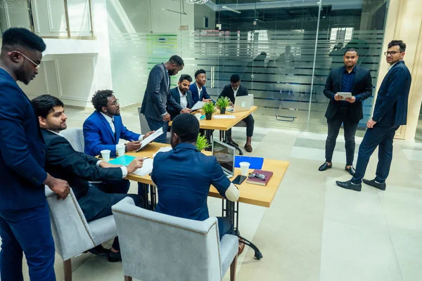 Grupo de gente internacional de negocios mirando el gráfico en el rotafolio en la oficina ecológica moderna —  Fotos de Stock