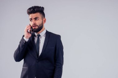 İtalyan genç başarılı yakışıklı siyah saçlı şık takım elbiseli adam stüdyoda beyaz arkaplanı izole ediyor.