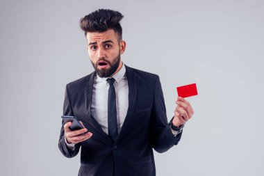 Stüdyoda şık takım elbiseli genç siyah saçlı adam beyaz arkaplanı izole ediyor.