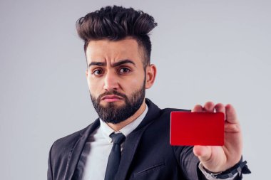 Stüdyoda kredi kartı tutan şık takım elbiseli Hintli genç, yakışıklı, siyah saçlı adam beyaz arka planı izole etti.