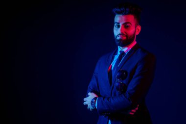 Stüdyoda şık takım elbiseli Hintli genç, yakışıklı, siyah saçlı adam beyaz arkaplanı izole ediyor.