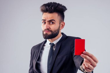 Stüdyoda kredi kartı tutan şık takım elbiseli Hintli genç, yakışıklı, siyah saçlı adam beyaz arka planı izole etti.