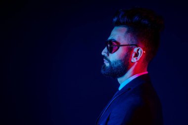 Stüdyoda şık takım elbiseli genç siyah saçlı adam beyaz arkaplanı izole ediyor.