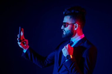 Stüdyoda şık takım elbiseli genç siyah saçlı adam beyaz arkaplanı izole ediyor.