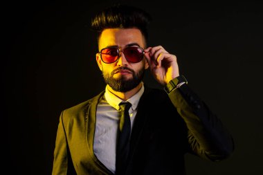 Stüdyoda şık takım elbiseli genç siyah saçlı adam beyaz arkaplanı izole ediyor.