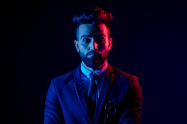 Stüdyoda şık takım elbiseli genç siyah saçlı adam beyaz arkaplanı izole ediyor.