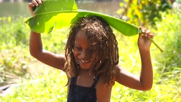 Mowgli indio chico con rastas pelo escondido sosteniendo plátano leav como una cubierta de lluvia en trópicos verde bosque fondo — Vídeos de Stock