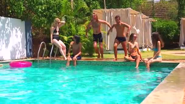 Група з шести молодих людей веселяться, розмовляють біля басейну, гарячий день — стокове відео