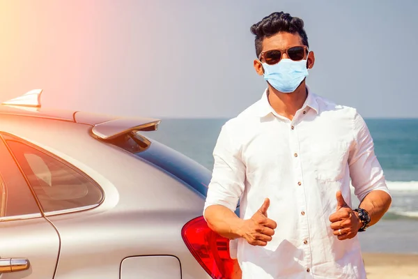Indian businessman in car outdoors on sea beach summer good day.a man in a white shirt and mask rejoicing buying a new car enjoying a vacation by the ocean