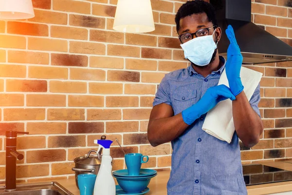 Tıbbi maskeli Afrikalı adam evde fırın kaputunu temizliyor. — Stok fotoğraf