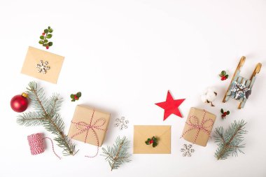 Noel çerçeve kompozisyon. Noel hediyesi, çam dalı, kırmızı topları, zarf, Beyaz ahşap kar taneleri, şerit ve kırmızı meyveler. Üstten Görünüm, düz yatıyordu, kopya alanı.