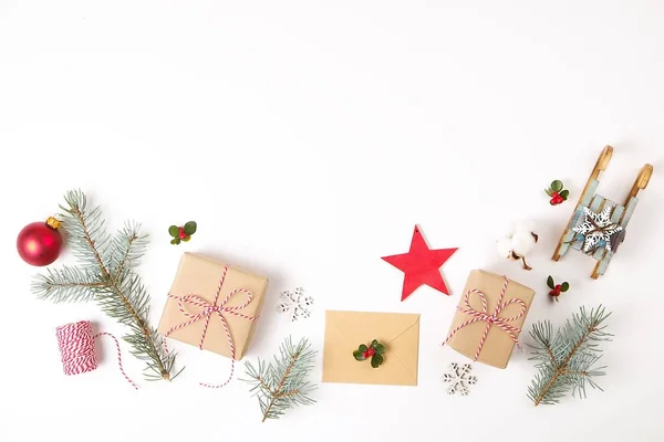 Χριστουγεννιάτικη σύνθεση καρέ. Δώρο Χριστουγέννων, κλαδί πεύκου, κόκκινες μπάλες, φάκελος, άσπρο ξύλινες νιφάδες χιονιού, κορδέλα και κόκκινα μούρα. Βάλτε το Top view, επίπεδη, αντίγραφο χώρου. — Φωτογραφία Αρχείου