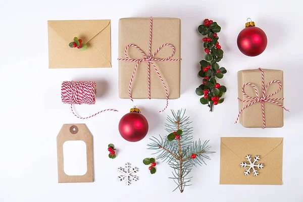 Weihnachtsrahmenkomposition. Weihnachtsgeschenke, Tannenzweig, rote Kugeln, Umschlag, weiße Holzschneeflocken, Schleife und rote Beeren. Draufsicht, flache Lage, Kopierraum — Stockfoto