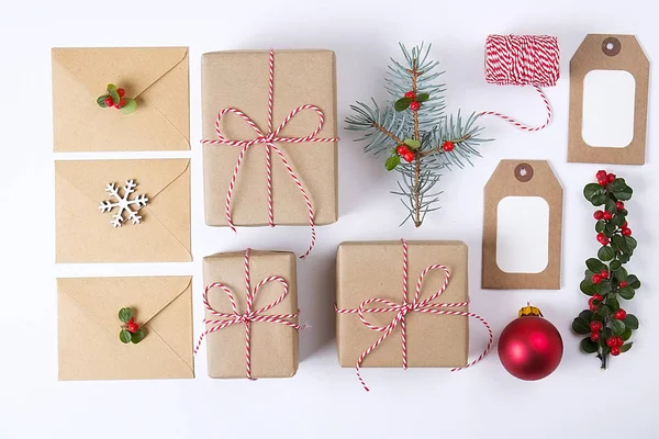 Weihnachtsrahmenkomposition. Weihnachtsgeschenke, Tannenzweig, rote Kugeln, Umschlag, weiße Holzschneeflocken, Schleife und rote Beeren. Draufsicht, flache Lage, Kopierraum — Stockfoto