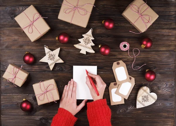 Вид зверху жіночих рук, пишучи лист до Санта дерев'яними тлі з різдвяні подарунки — стокове фото