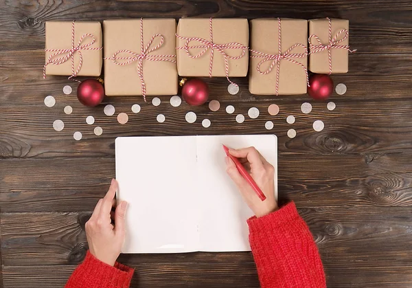 クリスマス プレゼントに木製の背景にサンタさんへ手紙を書く女性の手 — ストック写真