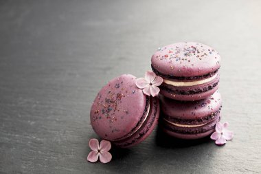 Macaron veya acıbadem kurabiyesi Fransız coockie beyaz dokulu arka plan bahar ile lila çiçekler, pastel renkler. 