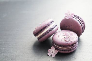 Macaron veya acıbadem kurabiyesi Fransız coockie beyaz dokulu arka plan bahar ile lila çiçekler, pastel renkler. 