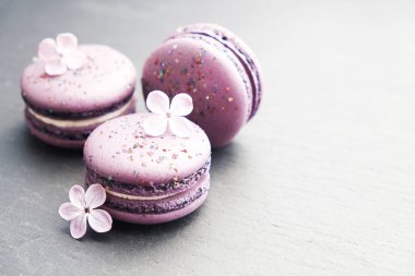 Macaron veya acıbadem kurabiyesi Fransız coockie beyaz dokulu arka plan bahar ile lila çiçekler, pastel renkler. 