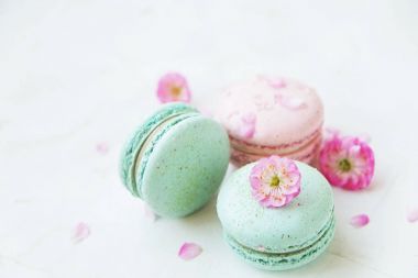 Macaron veya acıbadem kurabiyesi Fransız coockie beyaz dokulu arka plan bahar ile lila çiçekler, pastel renkler. 