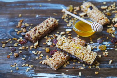 Ahşap masa üzerinde sağlıklı granola barlar. Çeşitli tahıl barlar ile fındık, tohumlar, kurutulmuş meyve ve çikolata ahşap masa, üstten görünüm.