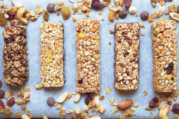 Cereal bars with dry fruits, nuts, granola and glass of milk on wooden background.Top view.Healthy homemade cereal bars with nuts, seeds and dried fruits on the wooden table.