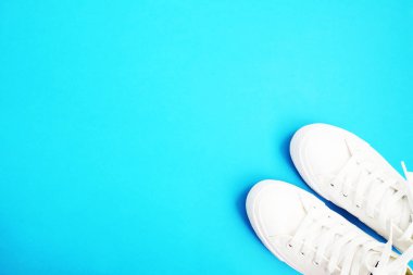 Kadınsı aksesuarları düz yatıyordu. Kadın Ayakkabı, çanta, smartphone ve pembe bir arka plan nöbette. Bej renk kadın aksesuarları. Metin alanı. Üstten Görünüm. Mavi zemin üzerine beyaz snickers.