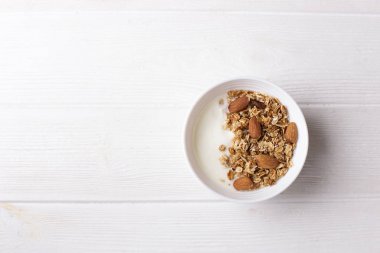 Kase tam tahıllı müsli Yoğurtlu beyaz arka planda, üstten görünüm