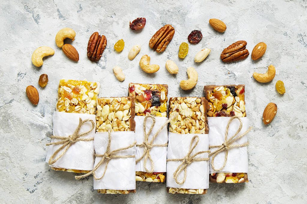 Healthy granola bars with nuts, seeds and dried fruits on the gray texture table, with copy space.