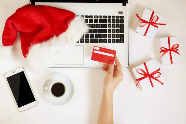 Flache Lage des Weihnachtsgeschenks mit Laptop-Tasse Kaffee-Kreditkarte in der Hand und sfnta claus Hut Draufsicht auf weißem Hintergrund, Kopierraum — Stockfoto