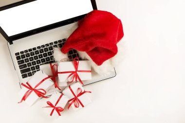 Çalışma alanıyla laptop ve Noel hediye ve santa şapka beyaz zemin üzerinde yatıyordu, en iyi görünüm, kopya alanı düz. İş Noel tatil kavramı, tatil online alışveriş