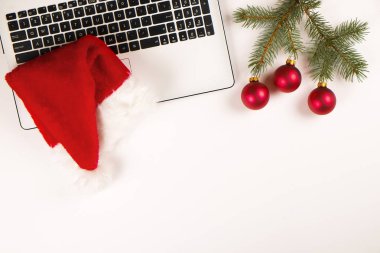 Çalışma alanıyla laptop ve Noel hediye ve santa şapka beyaz zemin üzerinde yatıyordu, en iyi görünüm, kopya alanı düz. İş Noel tatil kavramı, tatil online alışveriş