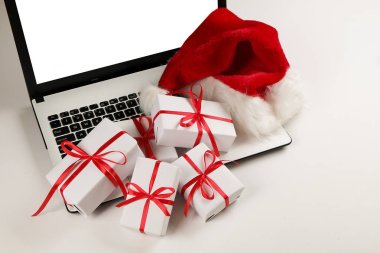 Çalışma alanıyla laptop ve Noel hediye ve santa şapka beyaz zemin üzerinde yatıyordu, en iyi görünüm, kopya alanı düz. İş Noel tatil kavramı, tatil online alışveriş