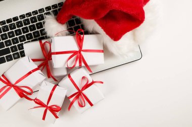 Çalışma alanıyla laptop ve Noel hediye ve santa şapka beyaz zemin üzerinde yatıyordu, en iyi görünüm, kopya alanı düz. İş Noel tatil kavramı, tatil online alışveriş