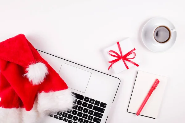 Arbeitsbereich mit Laptop und Weihnachtsgeschenk und Weihnachtsmütze auf weißem Hintergrund flach gelegt, Draufsicht, Kopierraum. Business Weihnachtsurlaub Konzept, Urlaub Online-Shopping — Stockfoto
